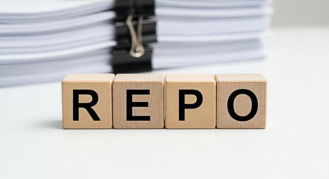 Wooden blocks spelling REPO on a white desk with a stack of documents representing financial repossession a serious and concerning situation in a clean and professional environment photo