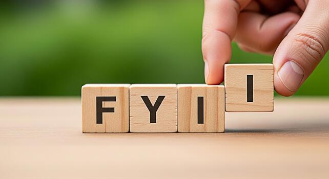 Hand arranging wooden blocks spelling FYI on a wooden surface against a blurred green background conveying a message of information knowledge and important updates in a clear and concise manner photo