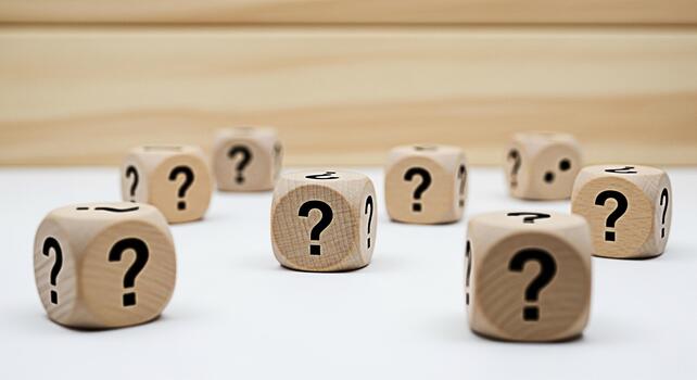 Wooden dice displaying question marks on a white surface representing uncertainty and the need for answers in a bright minimalist setting creating a sense of curiosity and problemsolving photo