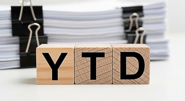 Wooden blocks displaying YTD in front of a stack of documents on a white desk representing yeartodate financial performance and business accounting with a focus on reporting and analysis photo