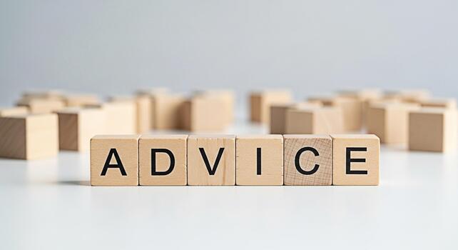 Wooden blocks spelling ADVICE sitting on a white surface with blurred blocks in the background conveying a message of guidance and support for business and personal growth photo