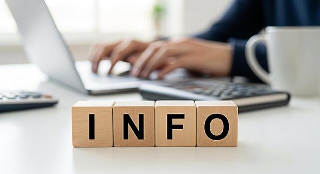 Person typing on a laptop in a bright office setting with wooden blocks spelling out INFO in the foreground conveying a sense of information knowledge and access to data photo