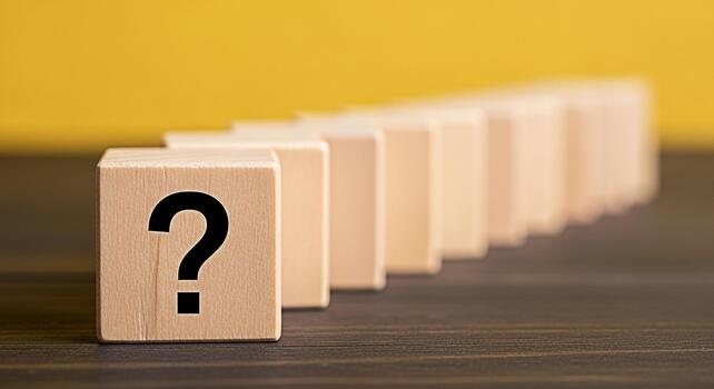 Wooden cube displaying a question mark leading a row of blocks on a wooden surface against a yellow backdrop symbolizing uncertainty and the search for answers in problemsolving and decisionmaking photo