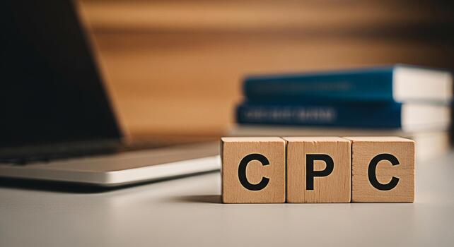 Wooden blocks spelling out CPC on a desk with a laptop and books in the background representing cost per click advertising and online marketing strategies in a modern business environment photo