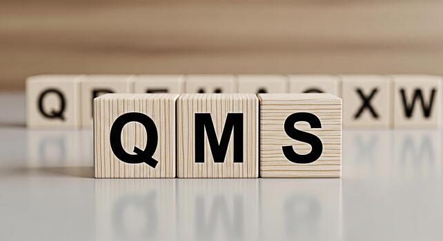 Wooden blocks displaying QMS on a reflective surface symbolizing Quality Management System in a corporate setting conveying a message of quality assurance and organizational excellence photo