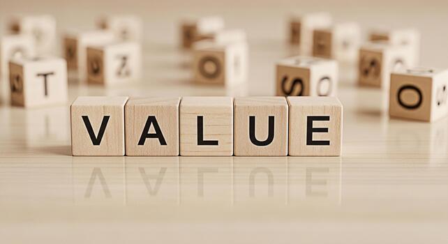 Wooden blocks spelling VALUE on a reflective surface surrounded by other letter blocks conveying a sense of importance worth and fundamental principles in a clean minimalist setting photo