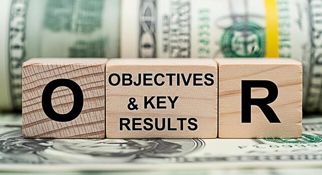 Wooden blocks displaying Objectives and Key Results resting on US dollar bills symbolizing financial goals and business strategy in a macro closeup shot conveying a sense of achievement and success photo