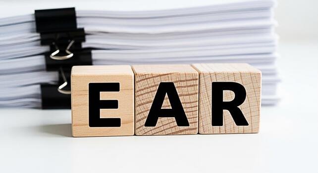 Wooden blocks spelling EAR in front of a stack of documents on a white surface representing the concept of active listening and attention to detail in business and communication creating a professiona photo