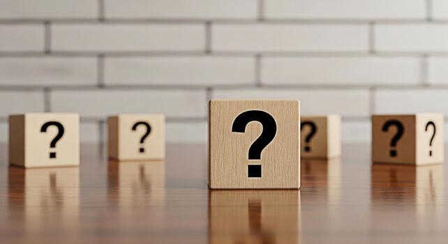 Wooden question mark blocks standing on a reflective wooden surface in front of a white brick wall symbolizing uncertainty inquiry and the search for answers in a clean and minimalist setting photo