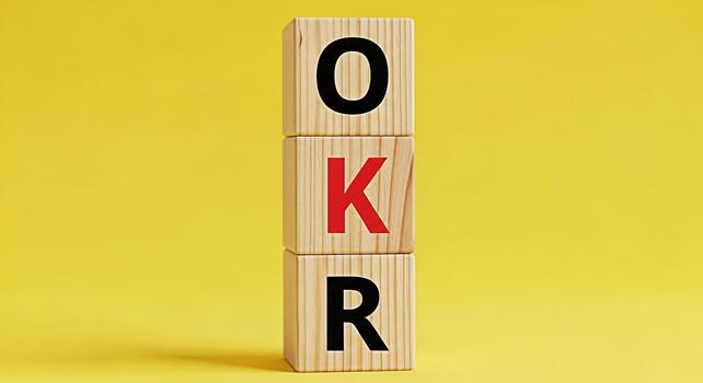Wooden blocks stacked vertically against a yellow background displaying the acronym OKR representing Objectives and Key Results a popular goalsetting framework for business strategy and success photo