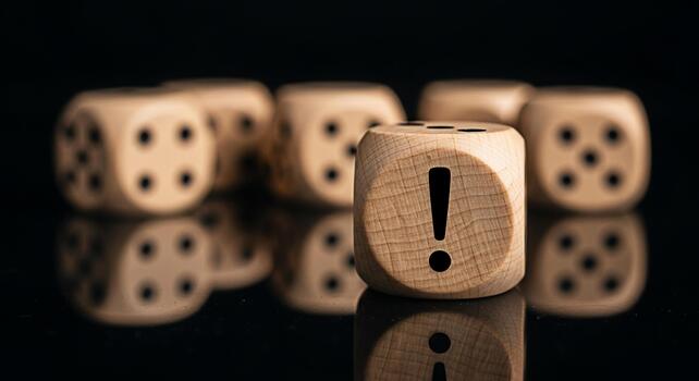 Wooden dice with an exclamation mark stands out on a reflective black surface symbolizing risk assessment and decisionmaking in a highstakes environment conveying a sense of urgency and importance photo