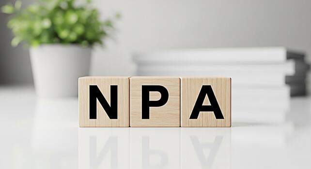 Wooden blocks displaying NPA on a white table in a bright office representing NonPerforming Assets financial risk and the importance of asset management in maintaining economic stability and growth photo