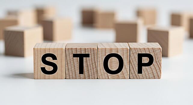 Wooden blocks spelling STOP on a white surface symbolizing a halt and warning in a clean minimalist setting conveying a strong message of caution and prevention with a sense of urgency photo