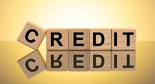 Wooden blocks spelling CREDIT on a reflective surface against a golden background representing financial responsibility and building a good credit score for a secure future photo