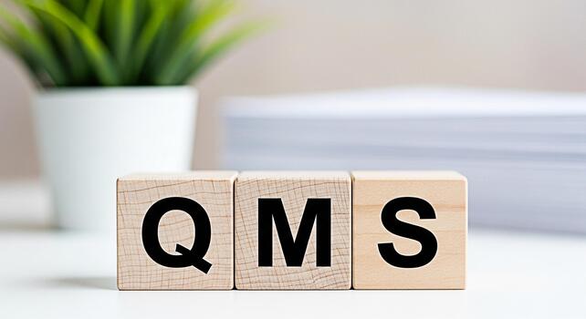 Wooden blocks displaying QMS on a bright white table in a modern office representing Quality Management System and business process improvement for efficiency and customer satisfaction photo