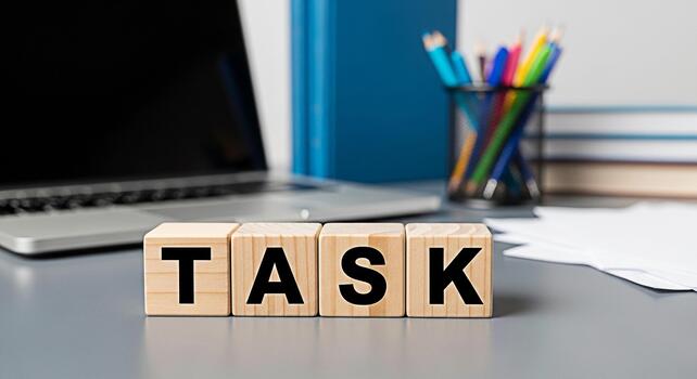 Wooden blocks spelling TASK on a modern office desk with a laptop and stationery representing focus and productivity in a professional workspace promoting efficiency and time management photo