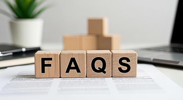 Wooden blocks displaying FAQs on a desk with a laptop plant and notebook representing frequently asked questions information and customer support in a modern office environment photo