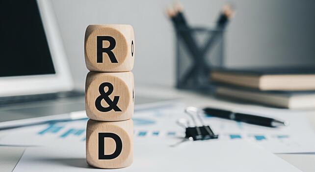 Wooden blocks displaying RD on a bright office desk with laptop and financial charts symbolizing research and development for business growth and innovation in a modern workspace environment photo