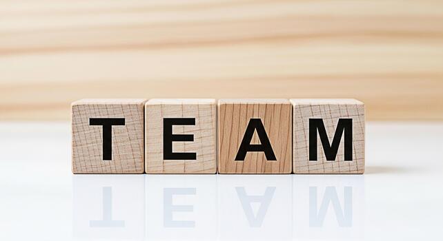Wooden blocks spelling TEAM on a reflective white surface against a light wood background symbolizing collaboration unity and the importance of teamwork in achieving common goals photo