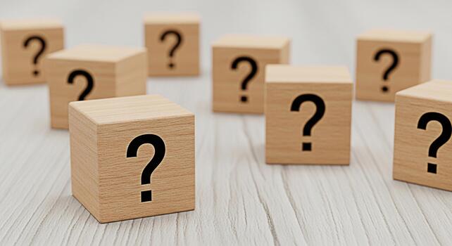 Wooden blocks displaying question marks on a textured white surface representing uncertainty and the need for problemsolving and decisionmaking in a bright and neutral environment photo