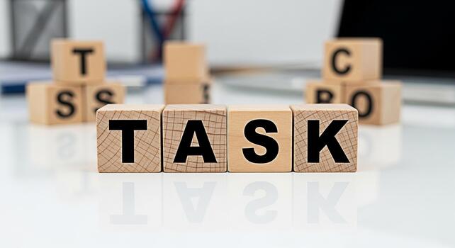 Wooden blocks spelling TASK on a white desk in a bright office environment representing focus and productivity with blurred background elements suggesting a busy workspace and a sense of accomplishmen photo