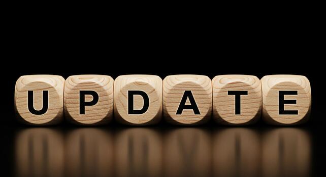 Wooden blocks spelling UPDATE on a reflective surface against a dark background symbolizing software updates system upgrades and the importance of staying current in a technological environment photo