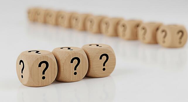 Wooden dice displaying question marks on a white surface symbolizing uncertainty and the need for answers creating a sense of mystery and intrigue in a minimalist setting perfect for illustrating comp photo