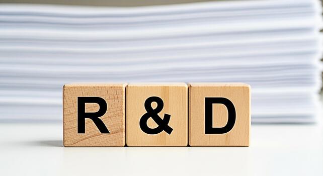 Wooden blocks displaying RD on a white table with a stack of papers in the background symbolizing research and development innovation and the pursuit of new knowledge in a clean professional setting photo