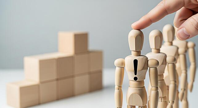 Hand selecting a wooden mannequin with an exclamation mark in a minimalist studio setting representing choice leadership and the importance of standing out from the crowd with a focus on career advanc photo