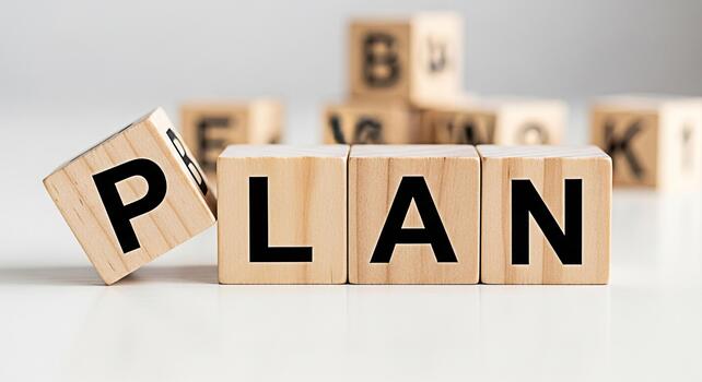 Wooden blocks spelling out PLAN on a white surface with other lettered blocks in the background symbolizing strategic planning and business development in a clean minimalist setting photo