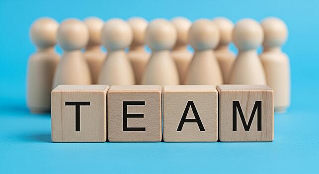 Wooden figures standing behind the word TEAM spelled out with wooden blocks on a blue background representing collaboration unity and the importance of teamwork in achieving common goals photo