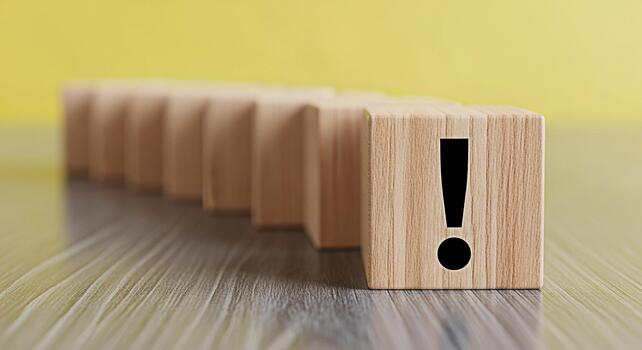 Wooden blocks displaying an exclamation point on a wooden surface against a yellow background symbolizing attention warning and the importance of problemsolving and critical thinking in business photo