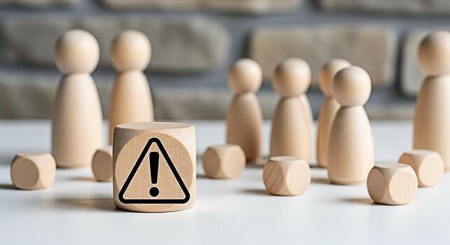 Wooden figures standing behind a warning sign on a table representing a potential risk or danger creating a sense of caution and awareness in a business or social context emphasizing the need for care photo