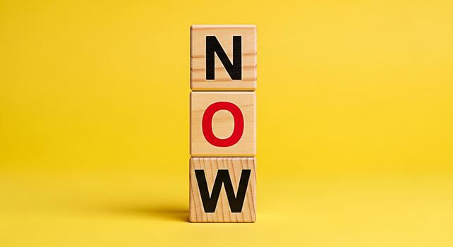 Wooden blocks spelling NOW stacked against a vibrant yellow background symbolizing urgency and immediate action creating a sense of motivation and the importance of seizing the moment inspiring prompt photo