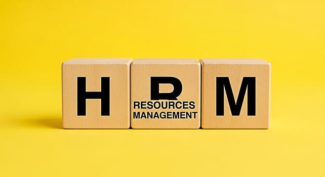 Wooden blocks displaying HRM Resources Management on a bright yellow background representing the importance of human resources and effective management in a modern business environment conveying a pro photo