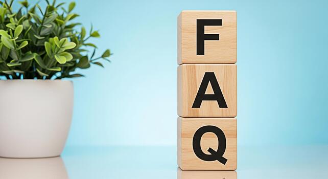 Wooden blocks spelling FAQ stacked on a reflective surface next to a potted plant against a light blue background representing frequently asked questions and customer support in a clean modern setting photo