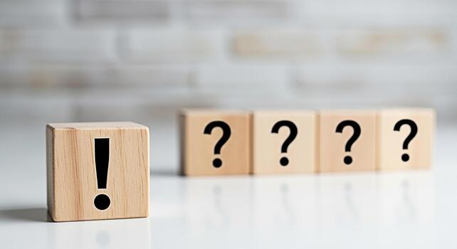 Wooden blocks displaying an exclamation mark stands out from the question marks on a white table against a blurred brick wall symbolizing solutions answers and problemsolving in a bright and clean set photo