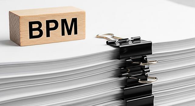 Wooden block displaying BPM next to a stack of papers secured with binder clips symbolizing business process management and efficiency in a clean organized office environment photo
