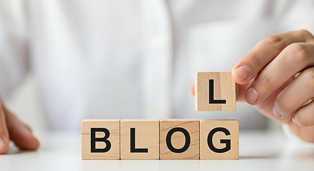 Closeup of a hand placing a wooden block with the letter L to complete the word BLOG on a white table symbolizing content creation and online communication in a bright minimalist setting photo