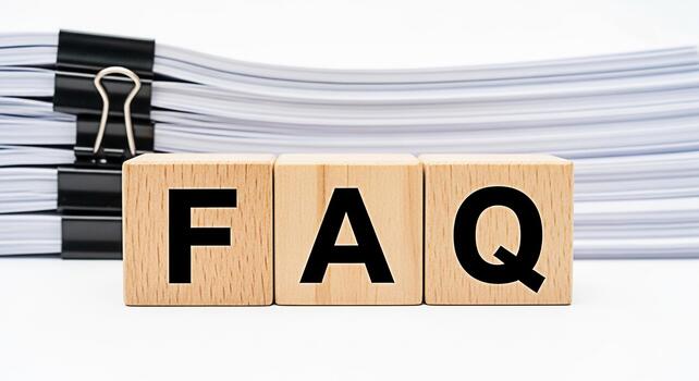 Wooden blocks displaying FAQ in front of a stack of documents representing frequently asked questions and information resources in a clean organized setting conveying clarity and accessibility photo