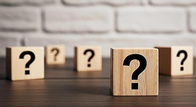 Wooden blocks displaying question marks on a dark wooden table against a white brick wall symbolizing uncertainty inquiry and the search for answers in a modern minimalist setting photo