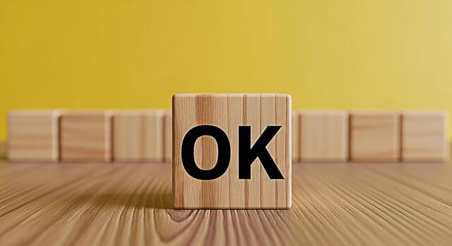 Wooden block displaying the word OK on a wooden surface against a bright yellow background symbolizing agreement acceptance and a positive affirmation in a simple and clear visual message photo