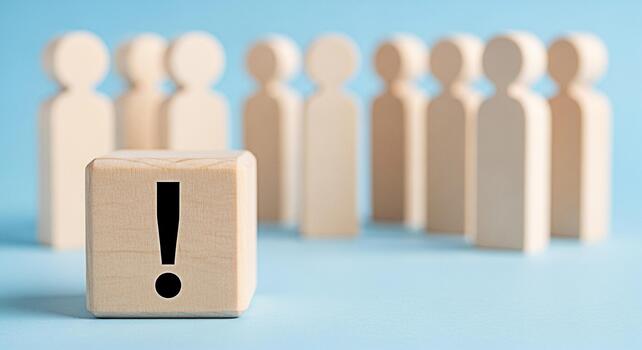 Wooden block displaying an exclamation mark stands out from a group of wooden figures on a blue background symbolizing warning attention and the importance of standing out from the crowd photo