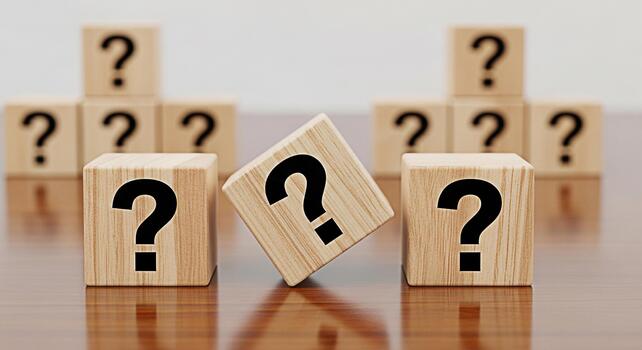 Wooden cubes displaying question marks on a reflective surface symbolizing uncertainty and the need for answers in a complex and challenging business environment creating a mood of inquiry and explora photo