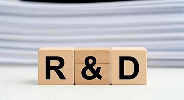 Wooden blocks displaying RD on a white table with a stack of papers in the background symbolizing research and development innovation and the importance of strategic planning in a modern business envi photo