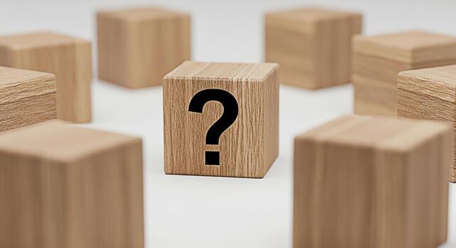 Wooden block displaying a question mark surrounded by other blocks on a white surface symbolizing uncertainty inquiry and the search for answers in a minimalist and thoughtprovoking composition photo