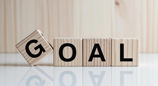 Wooden blocks spelling GOAL on a reflective surface symbolizing ambition and achievement in a bright minimalist setting conveying a message of motivation and success photo