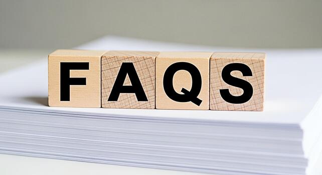Wooden blocks displaying FAQs on a stack of white paper symbolizing information access and customer support in a clean minimalist setting conveying clarity and helpfulness photo