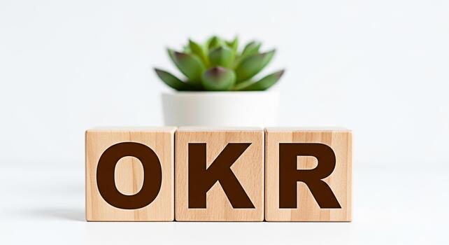 Wooden blocks displaying OKR on a white table with a succulent plant symbolizing objectives and key results for business strategy and goal setting in a clean modern office environment photo