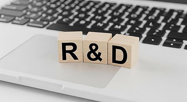 Wooden blocks spelling RD resting on a laptop keyboard in a bright minimalist workspace symbolizing research and development innovation and technological advancement in a modern business environment photo